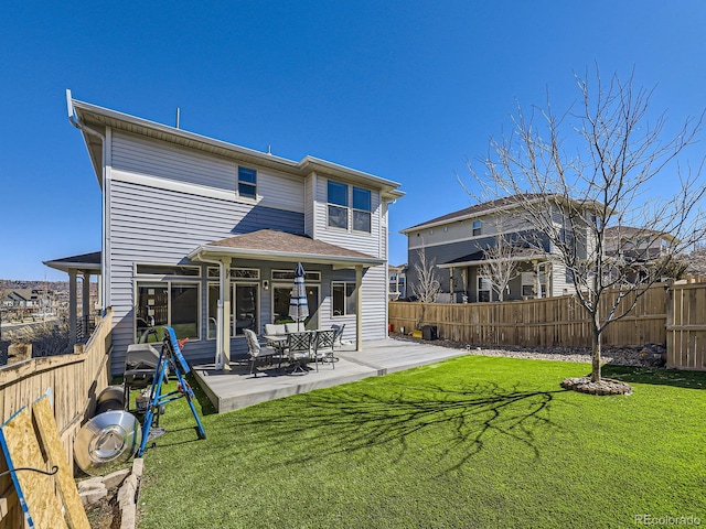 rear view of property featuring a lawn, a patio area, and a fenced backyard