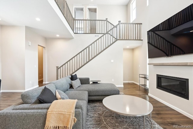 10557 Eby Cir, Lone Tree, CO 80124 - living room featuring stairs, wood finished floors, recessed lighting, a towering ceiling, and a glass covered fireplace