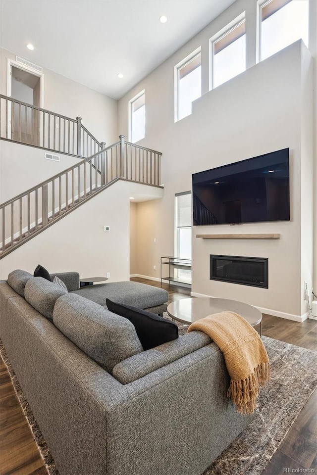 10557 Eby Cir, Lone Tree, CO 80124 - living room with wood finished floors, a glass covered fireplace, stairs, a high ceiling, and recessed lighting