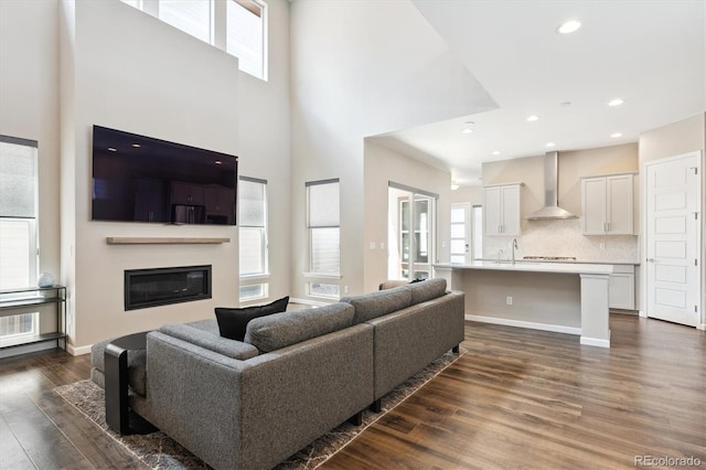 10557 Eby Cir, Lone Tree, CO 80124 - living area with dark wood-style flooring, healthy amount of natural light, a towering ceiling, a glass covered fireplace, and recessed lighting