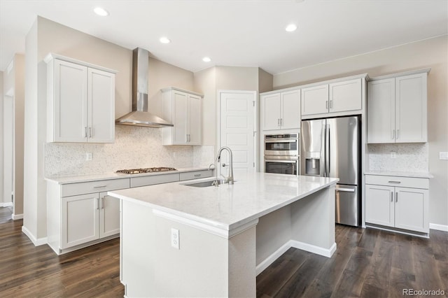 10557 Eby Cir, Lone Tree, CO 80124 - kitchen featuring stainless steel appliances, wall chimney range hood, tasteful backsplash, dark wood finished floors, and a kitchen island with sink