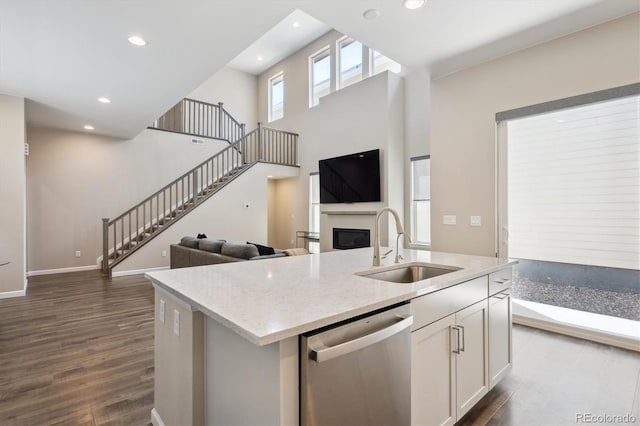 10557 Eby Cir, Lone Tree, CO 80124 - kitchen with stainless steel dishwasher, white cabinetry, open floor plan, a glass covered fireplace, and dark wood-style floors