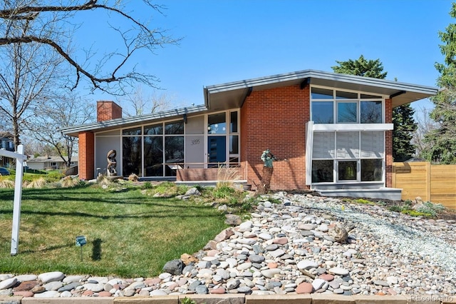 3895 Chimayo Rd, Littleton, CO 80123 - back of house with brick siding, a yard, a sunroom, and a chimney