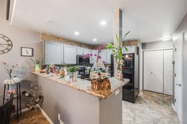 kitchen with light stone counters, kitchen peninsula, and black appliances