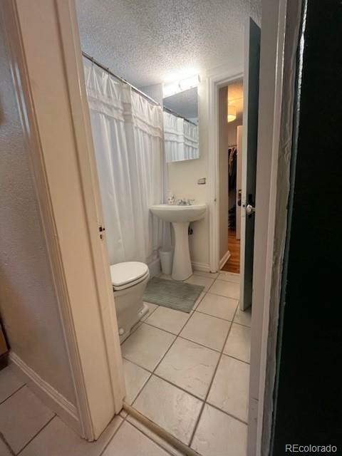 1024 E 14th Ave Unit 2, Denver, CO 80218 - full bath featuring tile patterned flooring, toilet, a shower with curtain, a textured ceiling, and baseboards