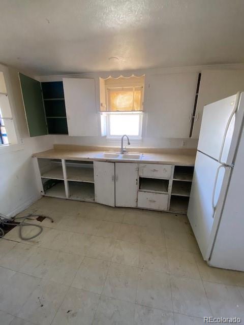 kitchen featuring white cabinets, open shelves, a sink, light countertops, and freestanding refrigerator