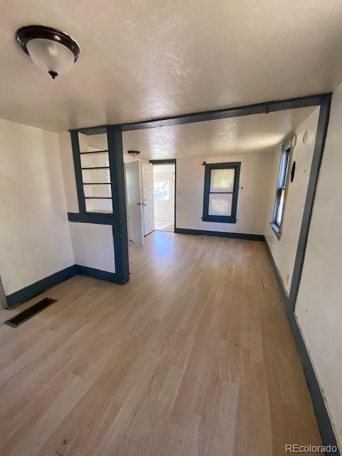 spare room featuring baseboards, visible vents, and light wood-style floors