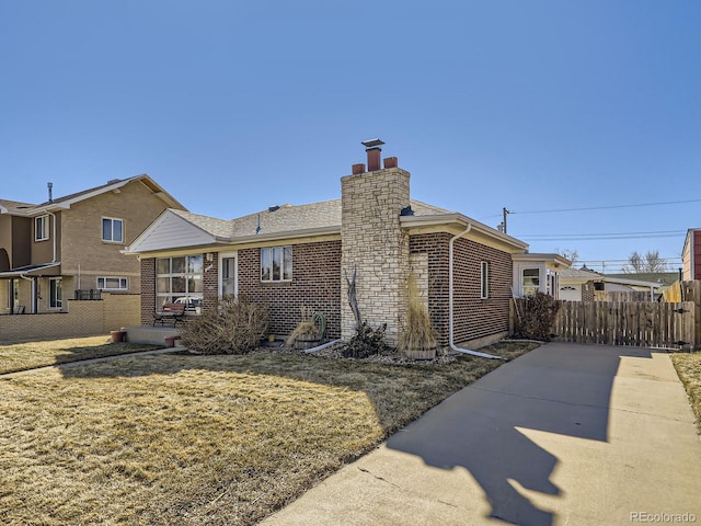 exterior space with brick siding, a chimney, fence, and a lawn