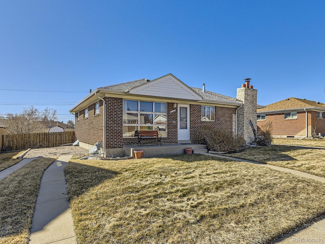 view of front of house featuring a front yard, brick siding, and fence