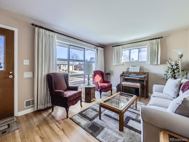 living room with light wood-type flooring, plenty of natural light, visible vents, and baseboards