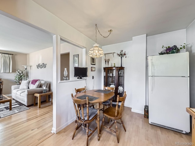 dining room with a chandelier, baseboards, and light wood finished floors