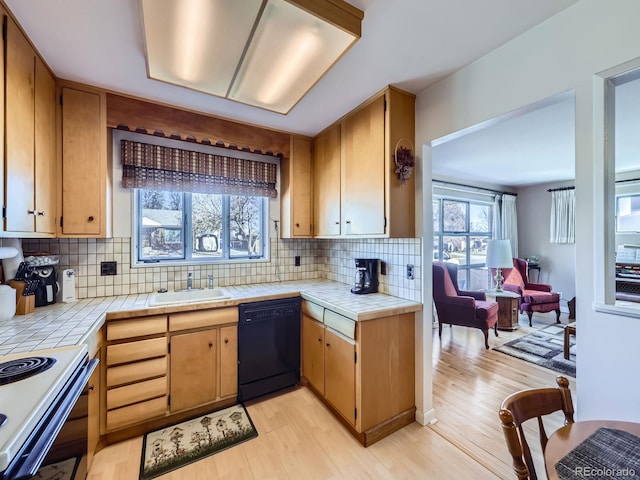 kitchen featuring black dishwasher, tile counters, white electric range, light wood-style flooring, and a sink