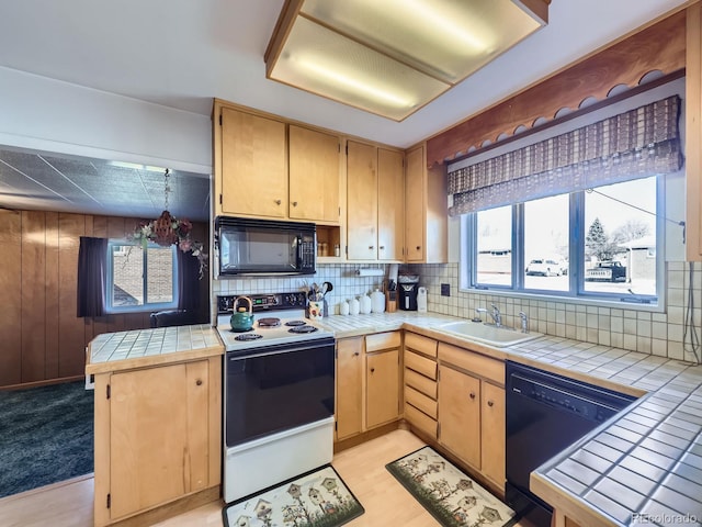 kitchen with black appliances, a sink, tile counters, and decorative backsplash