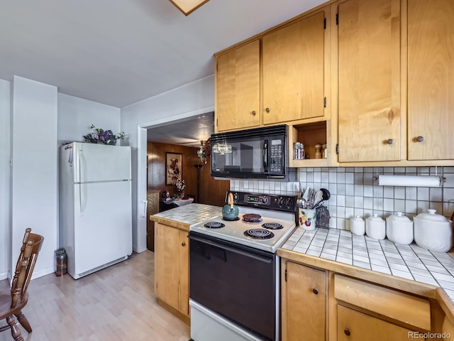 kitchen with black microwave, decorative backsplash, tile counters, freestanding refrigerator, and electric range oven