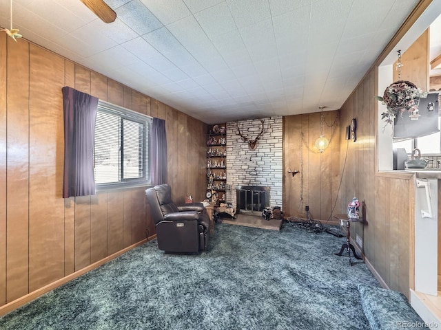 sitting room with a fireplace, carpet flooring, and wooden walls