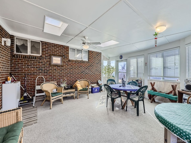 dining room featuring carpet, brick wall, a sunroom, and a ceiling fan