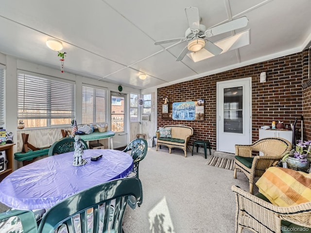 dining room with brick wall, a ceiling fan, and carpet flooring