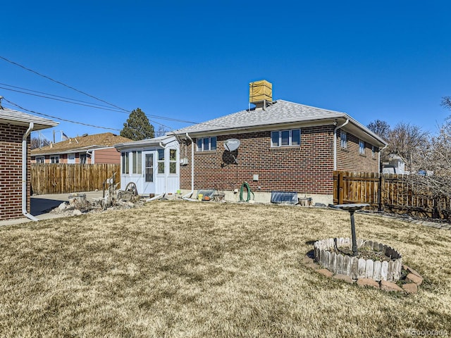 back of property featuring a lawn, a chimney, roof with shingles, fence, and brick siding