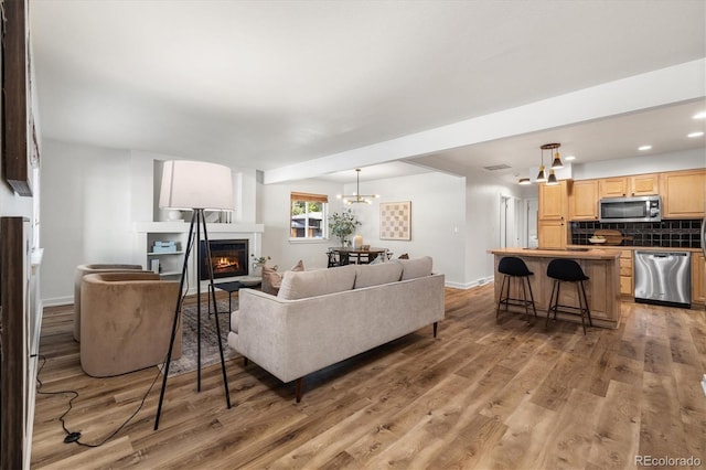 6290 Quail St, Arvada, CO 80004 - living room featuring light wood-type flooring, a warm lit fireplace, a chandelier, and recessed lighting