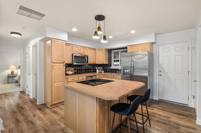 6290 Quail St, Arvada, CO 80004 - kitchen featuring appliances with stainless steel finishes, light brown cabinets, wood finished floors, and decorative backsplash