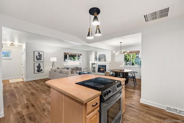 6290 Quail St, Arvada, CO 80004 - kitchen with stainless steel electric range, light brown cabinets, light wood-style floors, a warm lit fireplace, and open floor plan