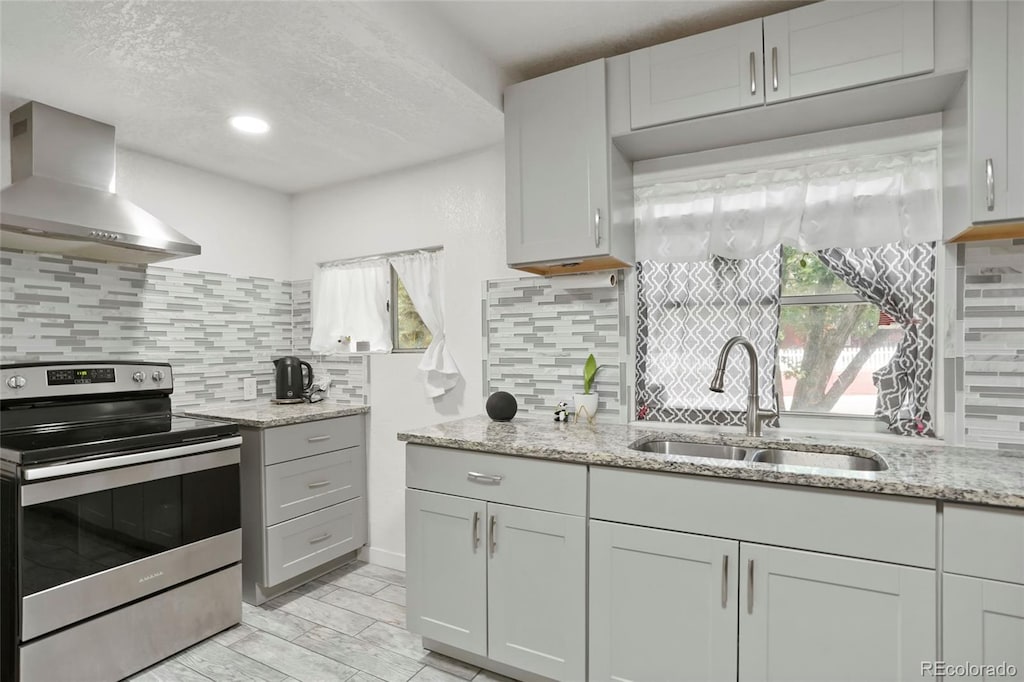 1070 S Newton St, Denver, CO 80219 - kitchen featuring stainless steel electric range, wall chimney exhaust hood, a sink, backsplash, and light stone counters