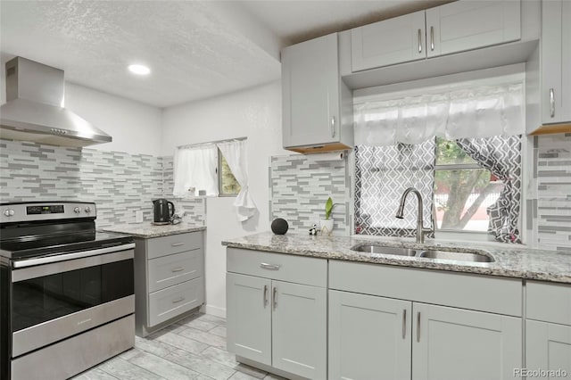 1070 S Newton St, Denver, CO 80219 - kitchen featuring stainless steel electric range, wall chimney exhaust hood, a sink, backsplash, and light stone counters