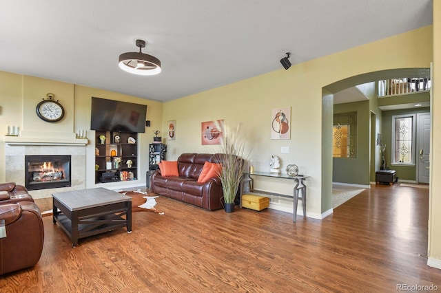 9536 W Avalon Dr, Littleton, CO 80127 - living room featuring arched walkways, wood finished floors, a fireplace, and baseboards