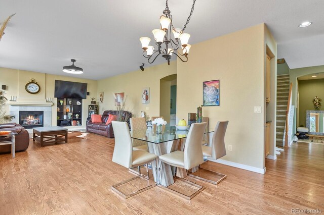 9536 W Avalon Dr, Littleton, CO 80127 - dining area featuring arched walkways, wood finished floors, a tile fireplace, baseboards, and a chandelier