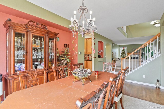 9536 W Avalon Dr, Littleton, CO 80127 - dining room with arched walkways, a chandelier, wood finished floors, stairs, and baseboards