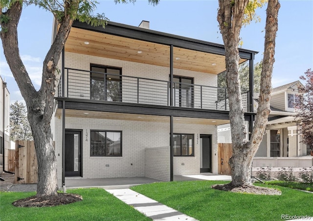 modern home featuring a balcony, a front lawn, and a patio area