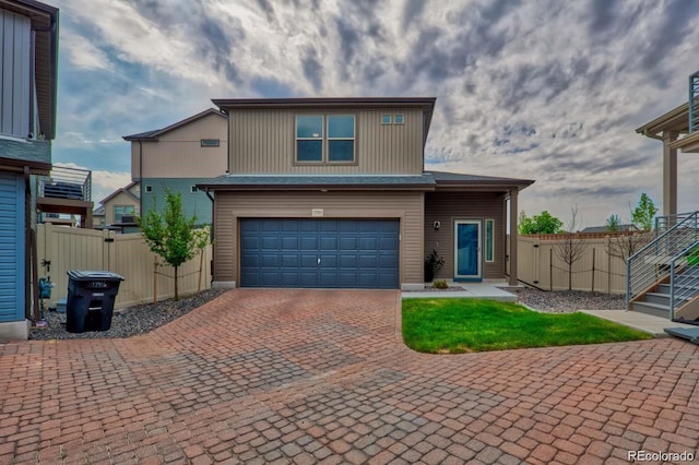 view of front facade featuring an attached garage, fence, and decorative driveway