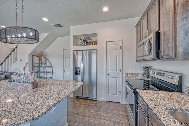 kitchen featuring light stone counters, appliances with stainless steel finishes, wood finish floors, and visible vents