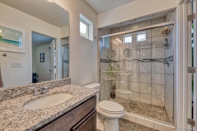 full bath with a textured wall, a shower stall, toilet, and vanity