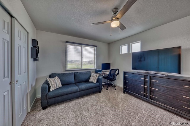 living area featuring a textured ceiling, carpet floors, a ceiling fan, and baseboards