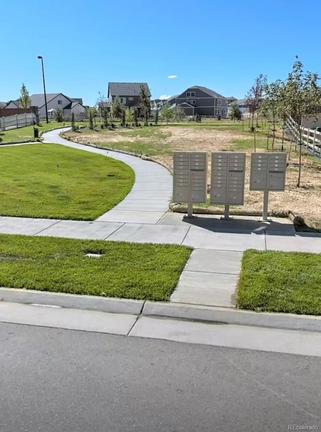 view of property's community featuring mail area and a yard