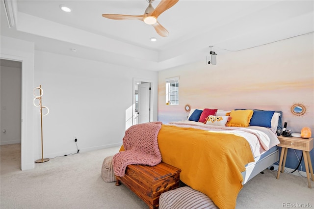 carpeted bedroom featuring a raised ceiling and ceiling fan