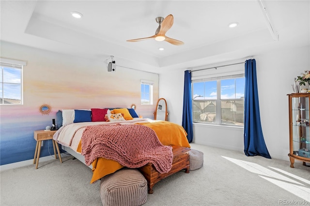 carpeted bedroom with a tray ceiling and ceiling fan