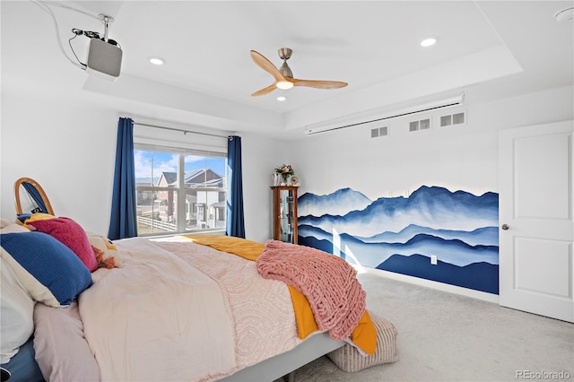 carpeted bedroom featuring a raised ceiling and ceiling fan