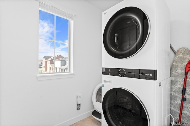 washroom featuring stacked washer and dryer and light tile patterned floors