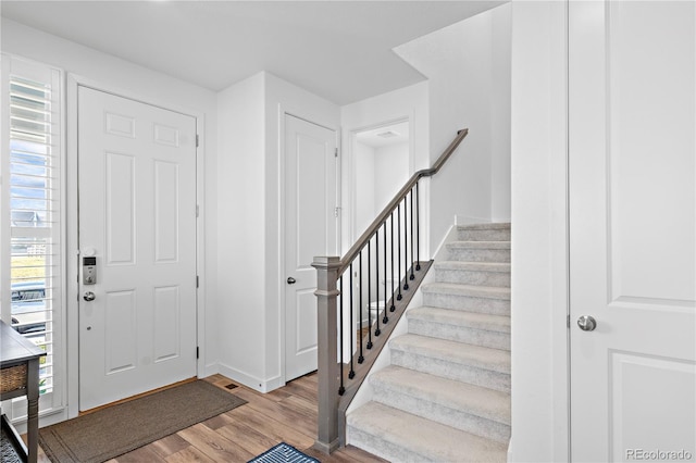 entryway featuring baseboards, stairs, and wood finished floors