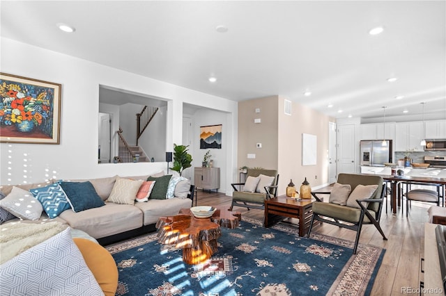 living room featuring stairs, recessed lighting, visible vents, and light wood-style flooring