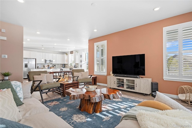 living room with recessed lighting, baseboards, wood finished floors, and a healthy amount of sunlight