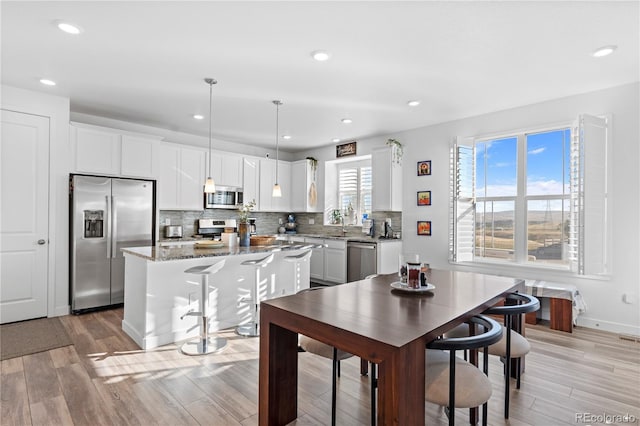 interior space featuring decorative backsplash, a center island, recessed lighting, light wood-style flooring, and appliances with stainless steel finishes