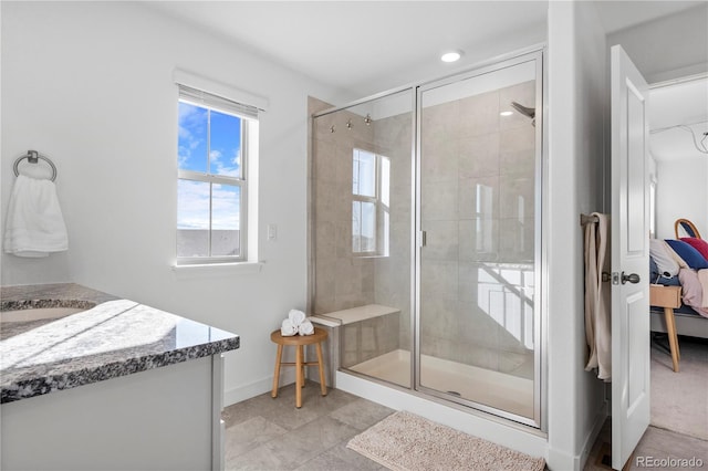 ensuite bathroom with tile patterned flooring, a stall shower, vanity, baseboards, and connected bathroom