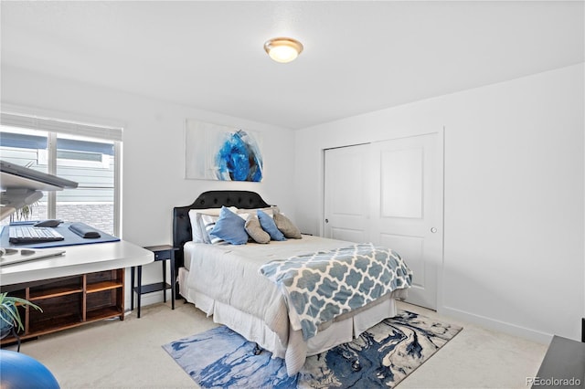 bedroom with baseboards, light carpet, and a closet