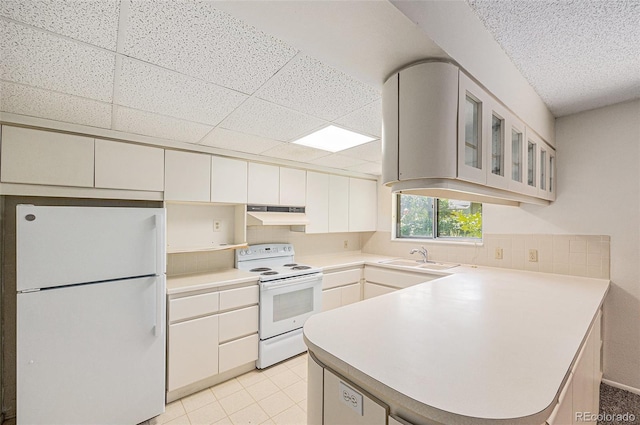 360 Upham St, Lakewood, CO 80226 - kitchen featuring white appliances, under cabinet range hood, a peninsula, glass insert cabinets, and tasteful backsplash