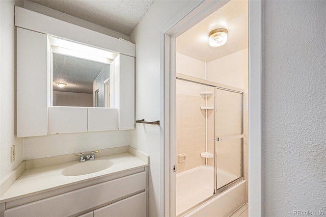 360 Upham St, Lakewood, CO 80226 - bathroom with shower / bath combination with glass door, vanity, a textured ceiling, and a textured wall