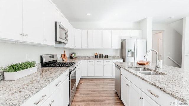 17850 W 94th Dr, Arvada, CO 80007 - kitchen with appliances with stainless steel finishes, a sink, white cabinetry, light wood finished floors, and light stone counters