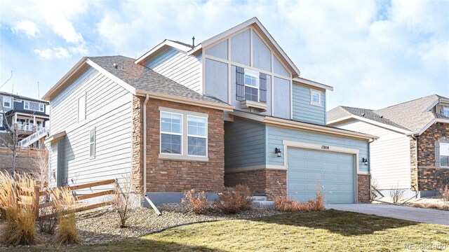 view of front of house featuring an attached garage, a shingled roof, concrete driveway, stone siding, and a front lawn